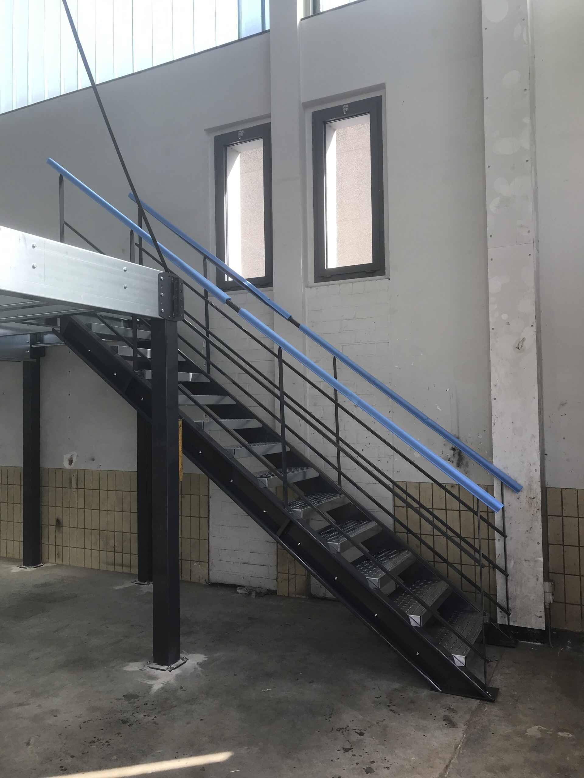 Stalen constructie met leuning naar de eerste verdieping van een industriële mezzanine