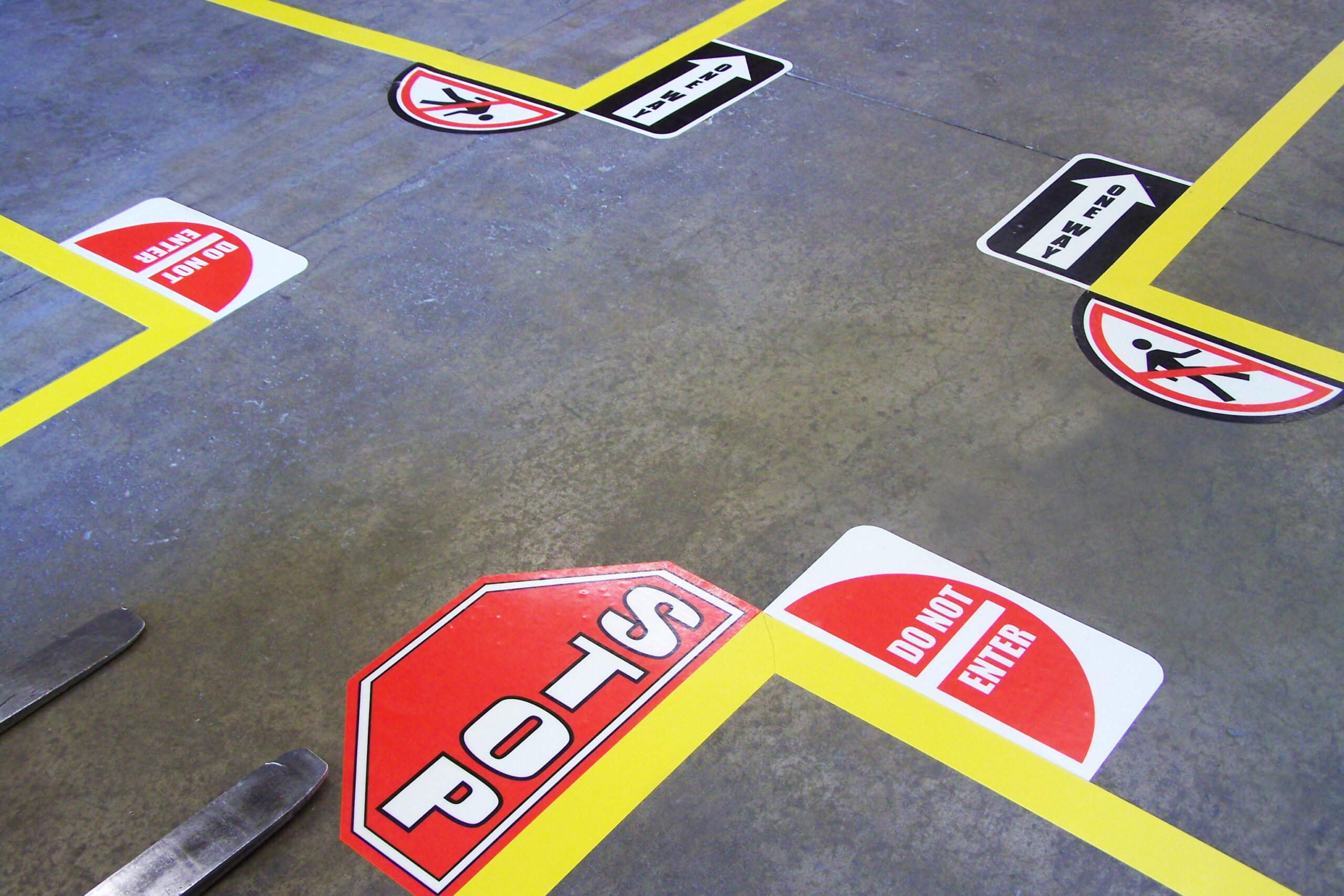 Betonnen magazijnvloer met gele hoekmarkeringen en meerdere rode zeshoekige stopbordstickets en waarschuwingsstickers / Sol d'entrepôt en béton avec des marquages d'angle jaunes et plusieurs autocollants stop hexagonaux rouges et autocollants d'avertissement