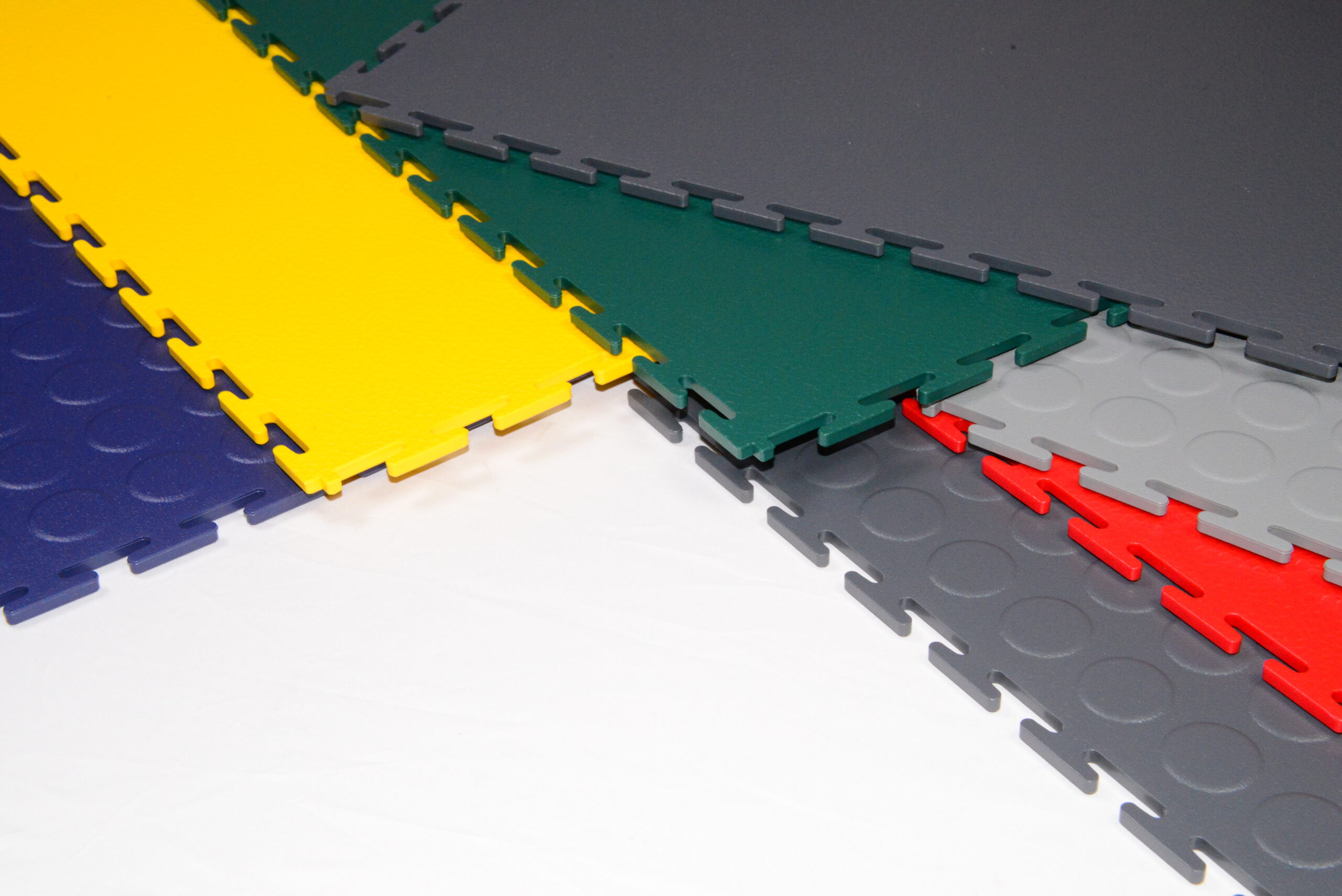 Gekleurde industriële klikvloertegels in blauw, geel, groen, rood en grijs met zwaluwstaartverbinding