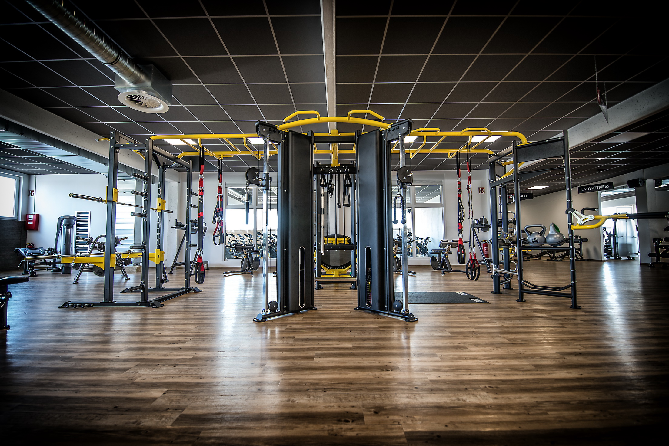 Moderne fitnessruimte met decoratieve vinyl vloer in een houtmotief en zwart gele finesstoestellen