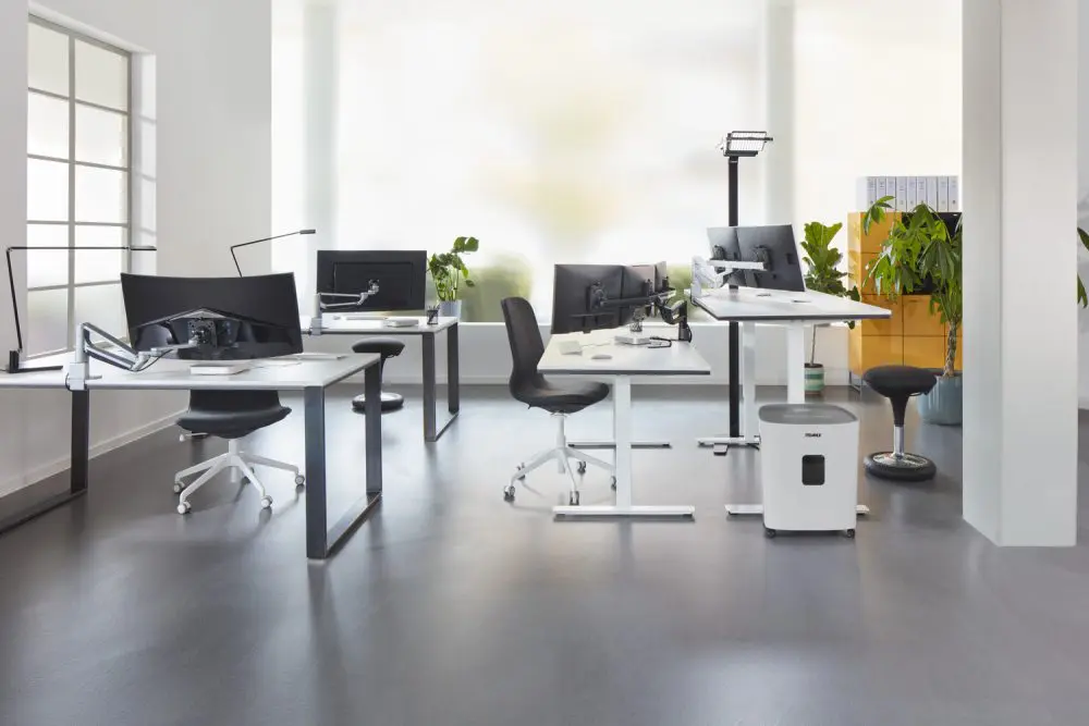 Moderne kantoorruimte met meerdere ergonomische werkplekken uitgerust met schermhouders, in hoogte verstelbare bureaus en ergonomische stoelen