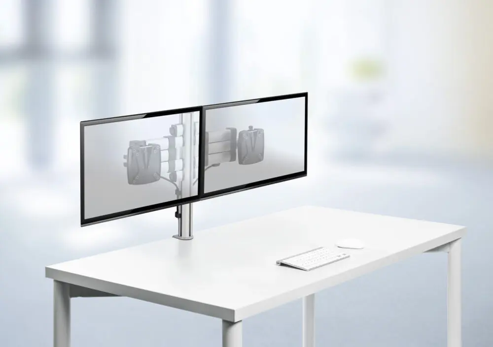 Productfoto van een dubbele ergonomische schermhouder bevestigd op een wit bureau, zonder schermen