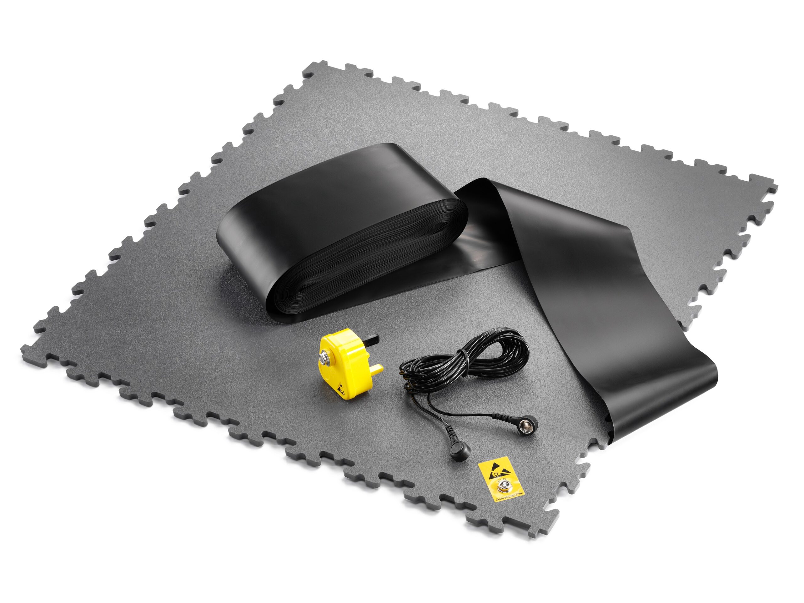 ESD-vloerkit bestaande uit donkergrijze puzzelvloertegels, zwarte aardingstape, tegel met drukknop, een gele aardingsstekker en een aardingskabel, voor de aanleg van een complete geleidende EPA-zone in elektrostatisch gevoelige werkomgevingen. Kit de revêtement de sol ESD comprenant des dalles de sol à emboîter gris foncé, du ruban de mise à la terre noir, une dalle avec bouton-poussoir, une fiche de mise à la terre jaune et un câble de mise à la terre, destiné à la mise en place d'une zone EPA conductrice complète dans les environnements de travail sensibles aux charges électrostatiques.