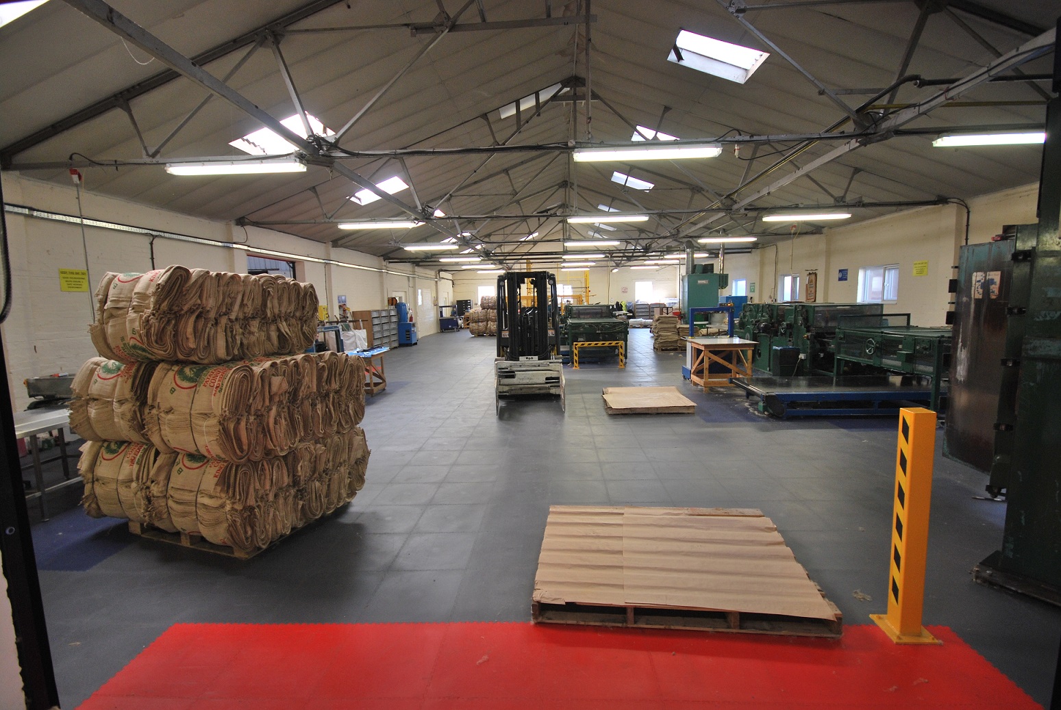 Grote productiehal met donkere heavy duty industriële vleor, heftruck en stapels materialen