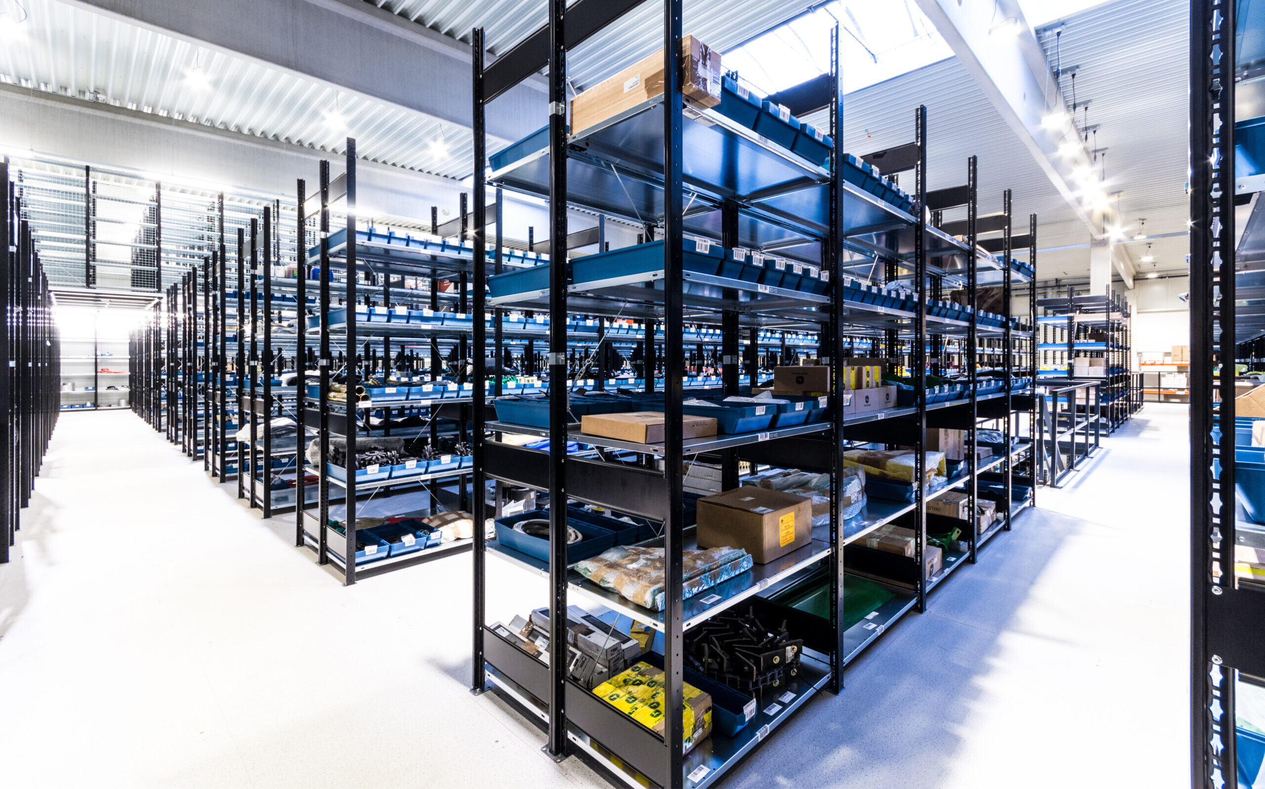 Zwarte legbordstellingen met blauwe opbergbakken in een overzichtelijk magazijn
