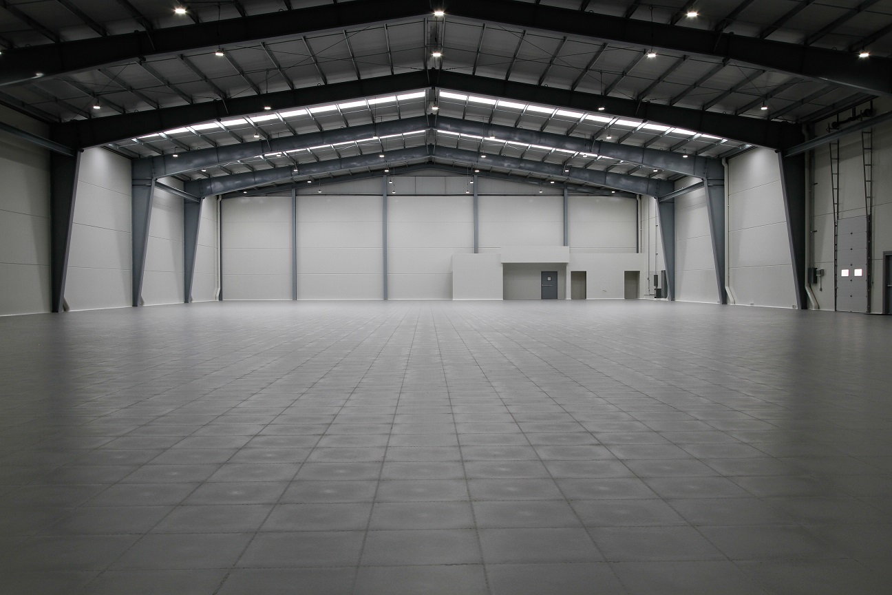 Grote lege industriële hal met een grijze klikvloer over de volledige oppervlakte