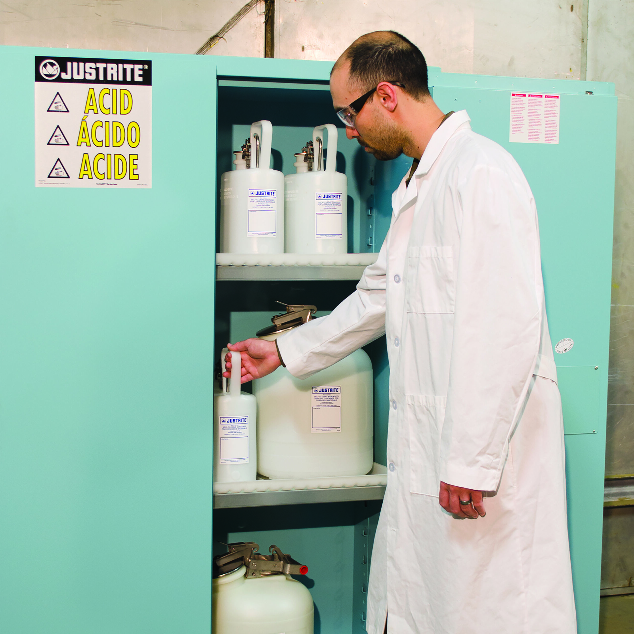 Laboratoriummedewerker die vaten opbergt in een blauwe veiligheidskast voor zuren en bijtende stoffen