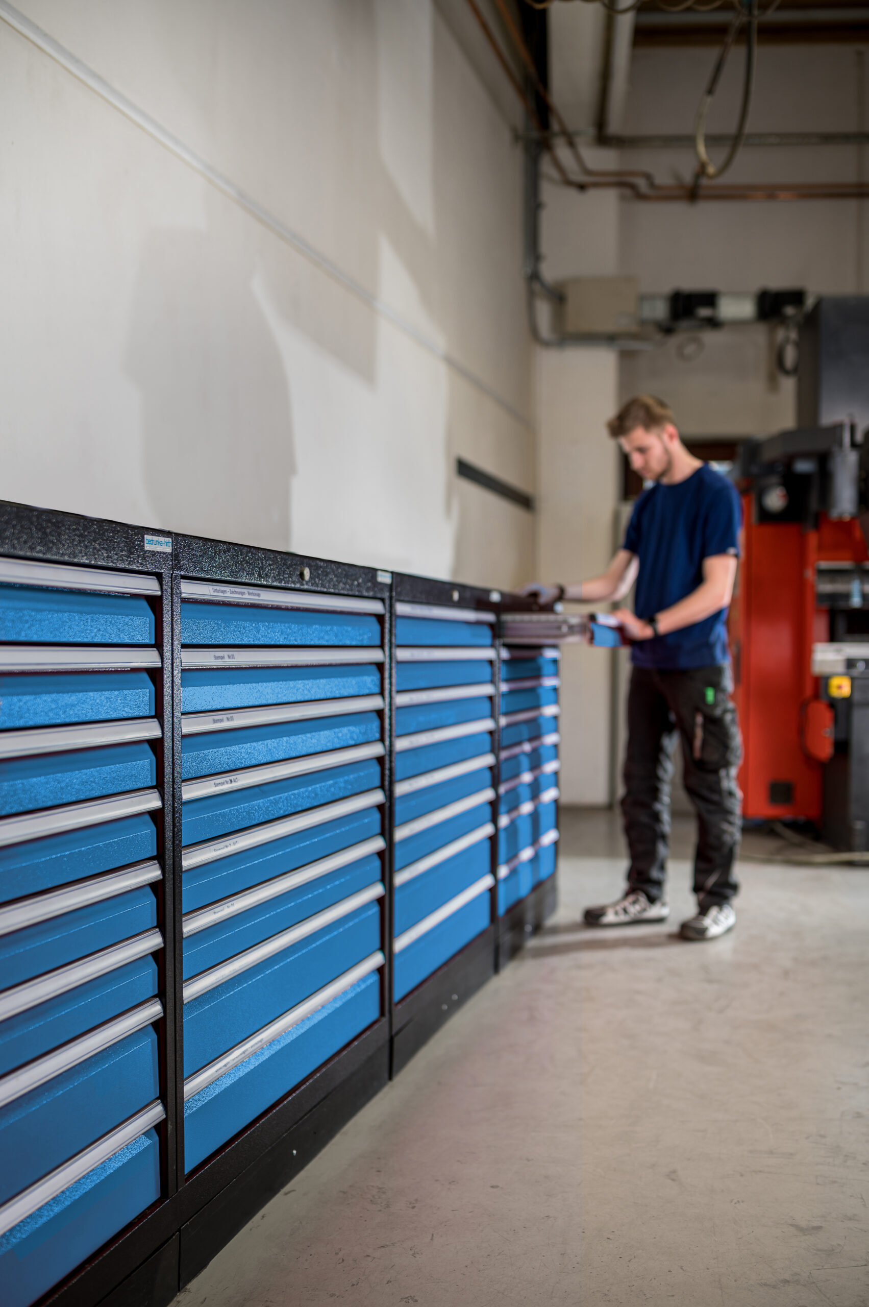 Close-up van van blauwe industriële ladekasten met gelabelde lades en een medewerker op de achtergrond - industriële kasten voor werkplaatsinrichting door AWP