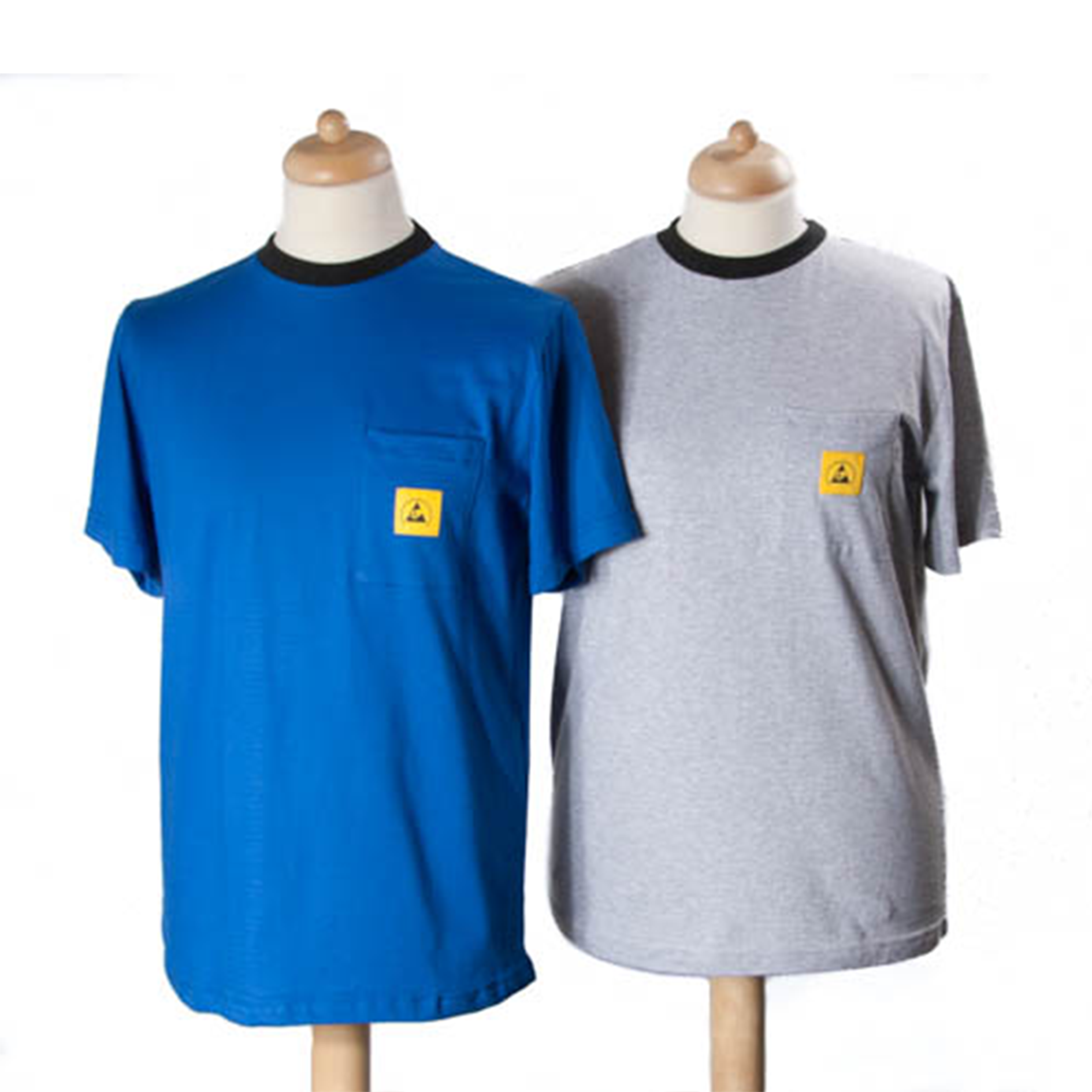 Twee ESD-T-shirts op mannequins: links een blauw model en rechts een grijs model, beide met ronde hals, donkere boordafwerking en een geel ESD-logo op de borstzak, ontworpen om elektrostatische oplading op de werkplek te voorkomen. Deux t-shirts ESD sur des mannequins : à gauche, un modèle bleu et à droite, un modèle gris, tous deux à col rond, avec des bords-côtes foncés et un logo ESD jaune sur la poche poitrine, conçus pour prévenir l'accumulation d'électricité statique sur le lieu de travail.