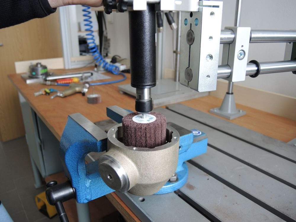 Deprag stationaire slijpmachine met schuurborstel gemonteerd op een pneumatische arm voor het bewerken van een gietstuk — AWP