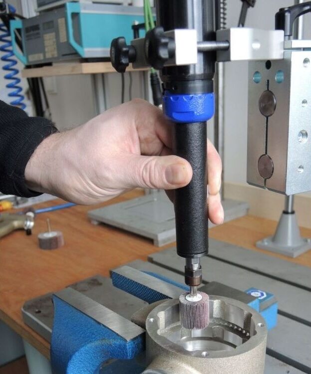 Handmatig bedienen van een Deprag stationaire slijpmachine bij het bewerken van een metalen werkstuk — AWP