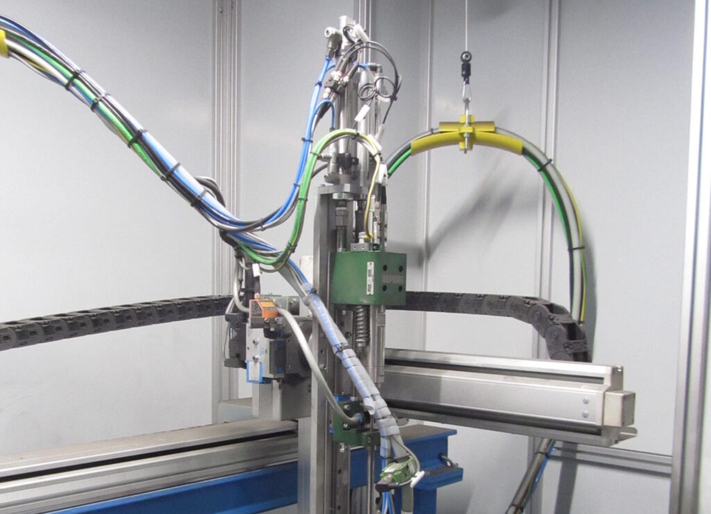 Zijaanzicht van een DEPRAG schroefmodule op een verticale lineaire Z-as met kabelgeleiders en schroeftoevoerslang in een geautomatiseerde schroefcel