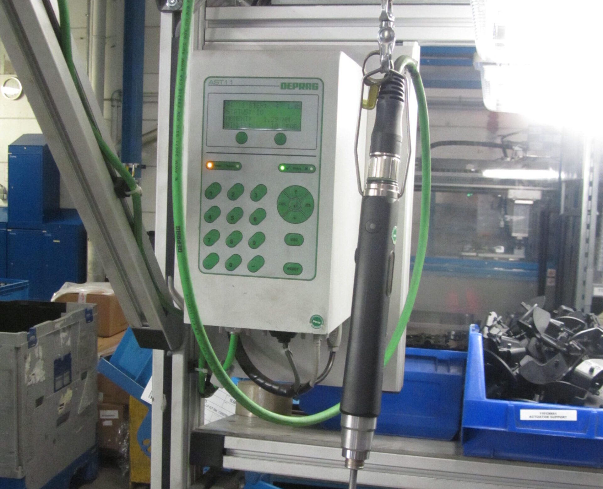 DEPRAG AST11 stuurkast met groen LCD-display en toetsenbord, gekoppeld aan een elektrische MINIMAT-schroevendraaier aan een veerbalancer in een automotive werkplaats