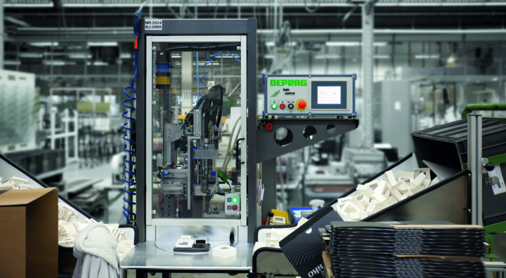 DEPRAG automatische schroefmachine met Logic Control besturingskast en transparante veiligheidsbehuizing in de productieomgeving van Niko, omgeven door witte kunststof opbouwdozen