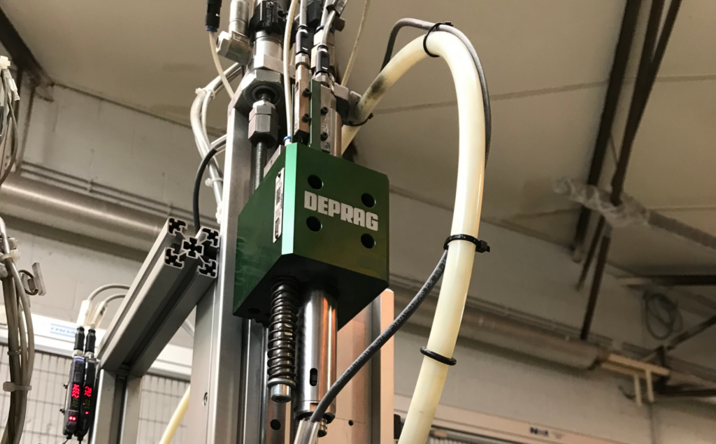 Close-up van een groene DEPRAG schroefmodule gemonteerd op een lineaire Z-as met veer en schroeftoevoerslang in een geautomatiseerde productie-installatie