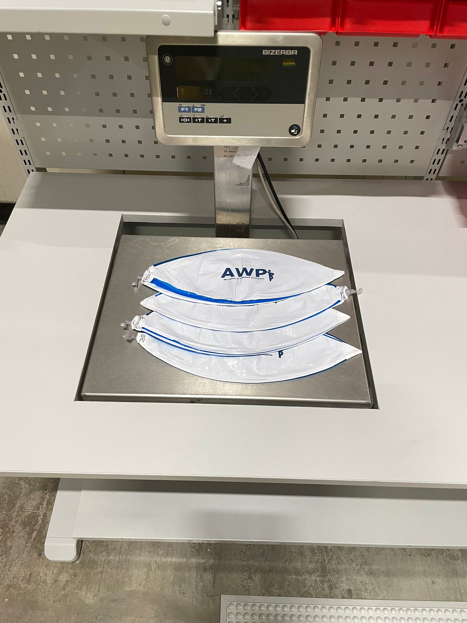 weegschaal geïntegreerd in een wit industrieel tafelblad met drie AWP-gebrandmerkte zakken op het weegplatform