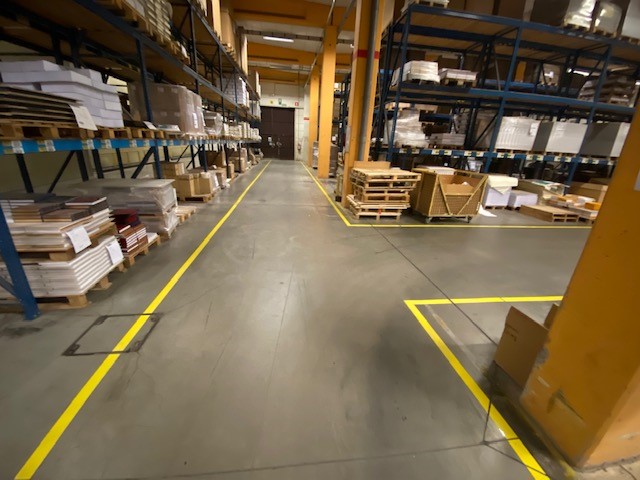 Gele vloermarkering op de productievloer van Brepols met duidelijk afgebakende wandelwegen en rijroutes