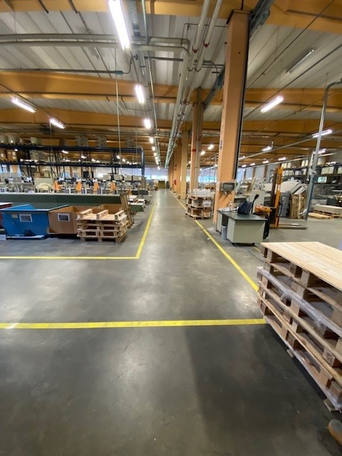 Gele vloermarkering die de werkvloer van Brepols structureert na een herindeling van de productieomgeving