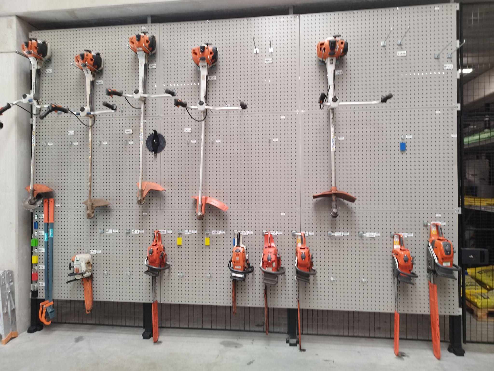 Verschillende stukken tuingereedschap georganiseerd op een grijs perfopaneel aan de muur