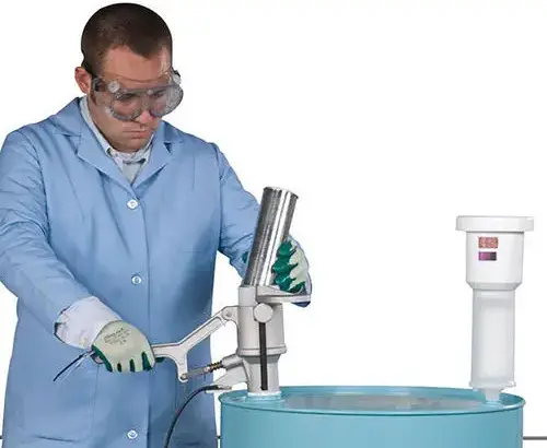 Laboratoriummedewerker die een gebruikte spuitbus verwerkt met het Justrite Aerosolv recyclingsysteem op een vat