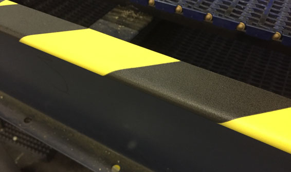 edge protector: Zwart-gele bumper guard bevestigd op de rand van een machine in een industriële omgeving